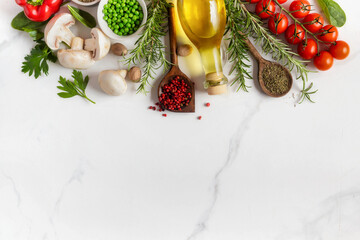 Healthy food cooking ingredients background with fresh vegetables, herbs, spices and olive oil on marble table with copy space top view