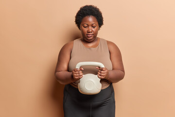 Healthy lifestyle. Studio shot of plump African american lady with short curly hair standing in...