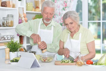 Obraz na płótnie Canvas senior couple making salad together at kitchen