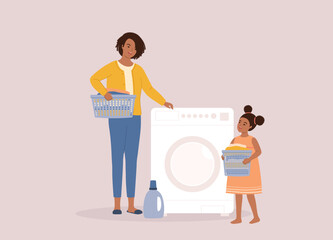 Little Black Girl With Laundry Basket Helping Her Mother To Put The Dirty Cloth Into The Washing Machine For Washing. Full Length.
