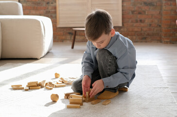 boy playing games building a tower of wooden cubes, logic game for child development. Family...