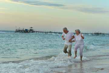 Fototapeta na wymiar Nice old couple running on sea beach