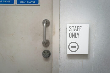 Staff only restricted area sign on the wall in grayscale tone. Sign and symbol for industrial working place object photo, selective focus.
