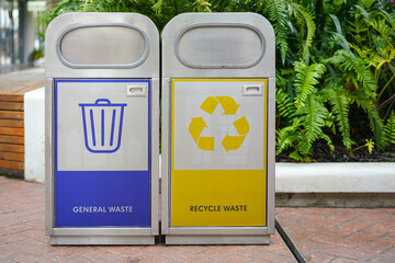Stainless steel trash bins with specific garbage types symbol which are placed a public place. 