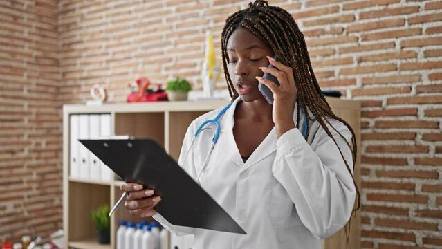 African american woman doctor arguing on smartphone reading medical report at the clinic