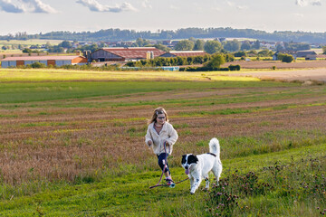 Obraz premium Little preschool girl walking with her dog. Cute kid and family pet in nature, fields and forest in late summer. Love and friendship between child and dog. Having fun together.