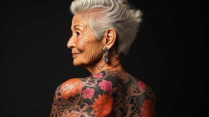 Fototapeta premium Inspiring elderly lady with white hair revealing back tattoos, oozing confidence on a plain backdrop, vibrantly symbolizing self-expression and grace in aging.