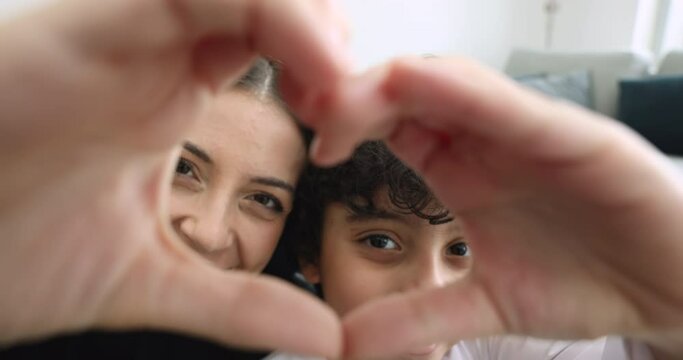 Loving Muslim mother and cute little son showing heart symbol with joined fingers, smile look at camera, close up faces view. Family express sincere feelings, charity, donation, unconditional love
