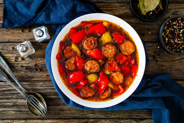 Delicious lecho - vegetables with sausages on wooden table
