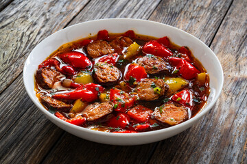 Delicious lecho - vegetables with sausages on wooden table
