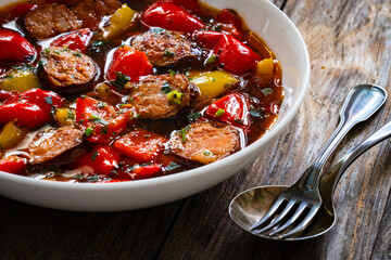 Delicious lecho - vegetables with sausages on wooden table
