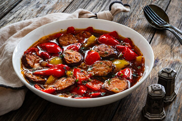 Delicious lecho - vegetables with sausages on wooden table

