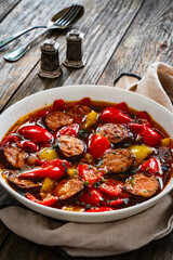 Delicious lecho - vegetables with sausages on wooden table
