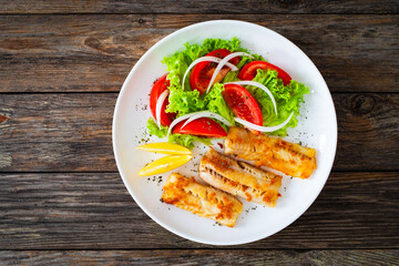 Seared cod loin and fresh vegetables on wooden table