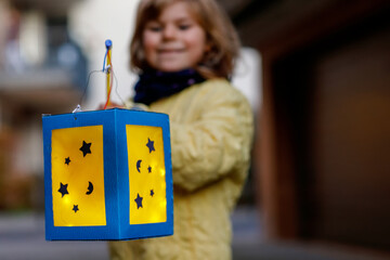 Closeup of little preschool kid girl holding selfmade traditional lanterns with candle for St....