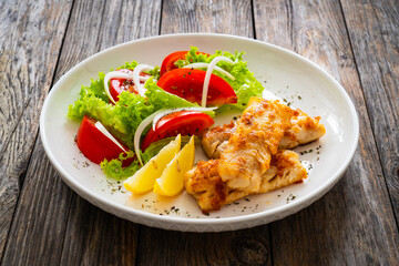 Seared cod loin and fresh vegetables on wooden table
