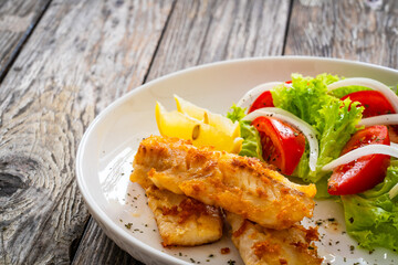 Seared cod loin and fresh vegetables on wooden table

