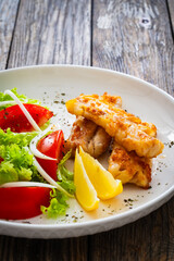 Seared cod loin and fresh vegetables on wooden table
