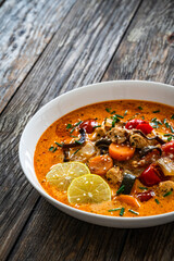 Tom Yum soup - Thai soup with chicken breast nuggets and noodles on wooden table
