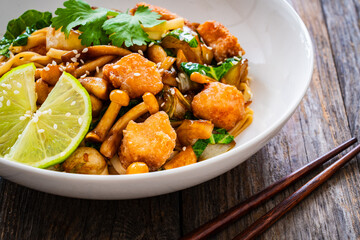 Asian food - chicken nuggets, noodles and fried shimeji mushrooms on wooden table
