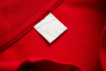 Blank white laundry care clothes label on red shirt fabric texture background