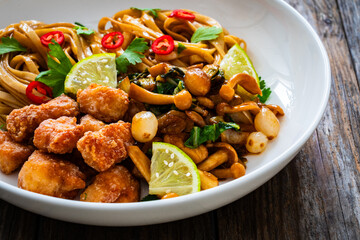 Asian food - chicken nuggets, noodles and fried shimeji mushrooms on wooden table
