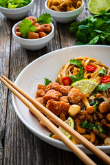 Asian food - chicken nuggets, noodles and fried shimeji mushrooms on wooden table
