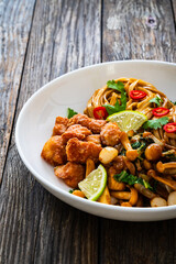 Asian food - chicken nuggets, noodles and fried shimeji mushrooms on wooden table
