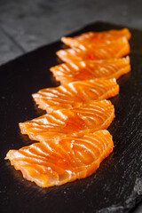 pieces of sliced fresh salmon on a dark stone tray