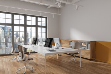 Stylish coworking interior with pc monitors and drawer, window. Mockup wall