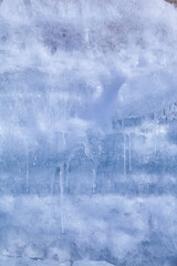 Texture of winter ice on a stone cliff. Blue natural ice background