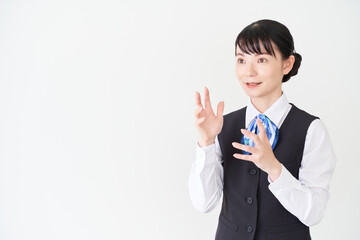 説明するベストにリボンタイの制服を着た、受付業務、事務業務の女性