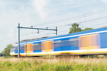 Sprinter train rushes by at high speed, blurred by long exposure in Arnhem in the Netherlands