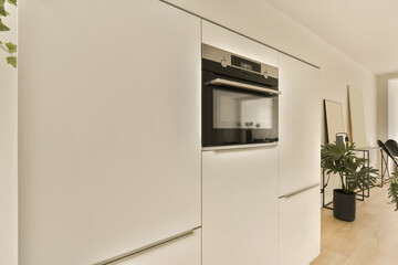 a kitchen and dining area in a modern apartment with white walls, wood flooring and an oven on the wall