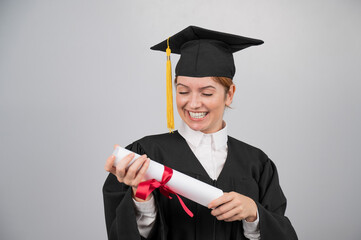 Smiling woman in graduation gown holding diploma on white background. 