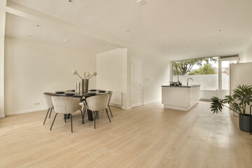 a living room with wood flooring and white walls in the background is an open kitchen, dining table and two chairs