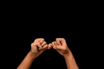 Two hands hooking each other little finger on black background, symbol of promise or pardon