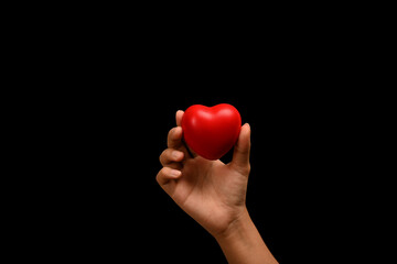 Hand holding red heart over black background. Health care, insurance, love, charity and donation concept