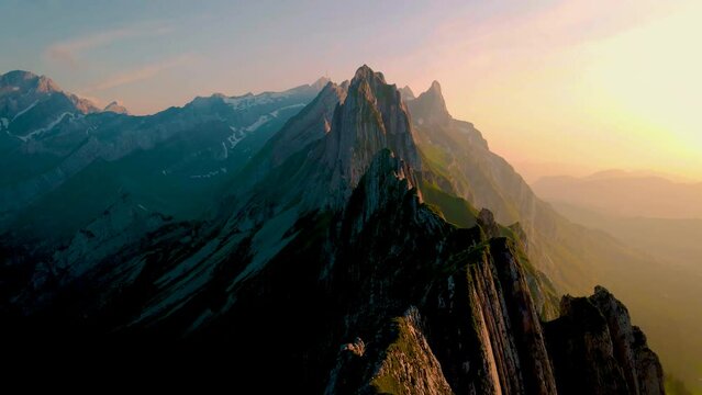 Couple at the hedge of a mountain watching the sunset, Schaeffler mountain ridge swiss Alpstein, Appenzell Switzerland, a steep ridge of the majestic Schaeffler peak, 