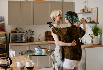 Young lesbian couple dancing together in the kitchen at home