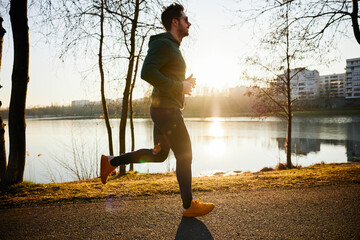 Man jogging in park during autumn or winter sunset