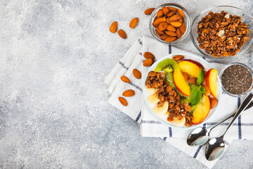 Bowl of granola with yogurt and fresh berries on a texture table. Yogurt berries, acai bowl, spirulina bowl. Healthy food, balanced breakfast. Strawberries, blueberries, kiwi, peach, almonds and chia.