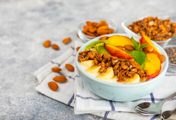 Bowl of granola with yogurt and fresh berries on a texture table. Yogurt berries, acai bowl, spirulina bowl. Healthy food, balanced breakfast. Strawberries, blueberries, kiwi, peach, almonds and chia.