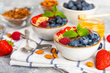 Bowl of granola with yogurt and fresh berries on a texture table. Yogurt berries, acai bowl, spirulina bowl. Healthy food, balanced breakfast. Strawberries, blueberries, kiwi, peach, almonds and chia.