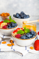 Bowl of granola with yogurt and fresh berries on a texture table. Yogurt berries, acai bowl, spirulina bowl. Healthy food, balanced breakfast. Strawberries, blueberries, kiwi, peach, almonds and chia.