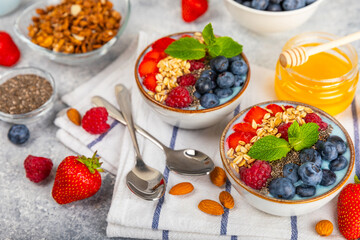 Bowl of granola with yogurt and fresh berries on a texture table. Yogurt berries, acai bowl, spirulina bowl. Healthy food, balanced breakfast. Strawberries, blueberries, kiwi, peach, almonds and chia.