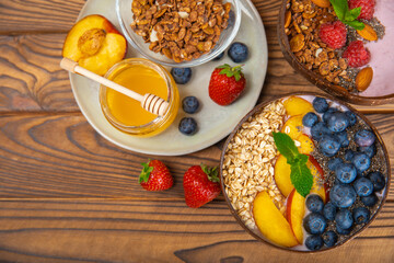 Bowl of granola with yogurt and fresh berries on a texture table. Yogurt berries, acai bowl, spirulina bowl. Healthy food, balanced breakfast. Strawberries, blueberries, kiwi, peach, almonds and chia.