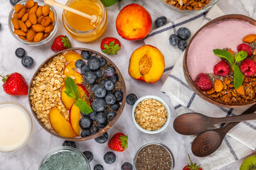 Bowl of granola with yogurt and fresh berries on a texture table. Yogurt berries, acai bowl, spirulina bowl. Healthy food, balanced breakfast. Strawberries, blueberries, kiwi, peach, almonds and chia.