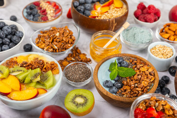 Bowl of granola with yogurt and fresh berries on a texture table. Yogurt berries, acai bowl, spirulina bowl. Healthy food, balanced breakfast. Strawberries, blueberries, kiwi, peach, almonds and chia.