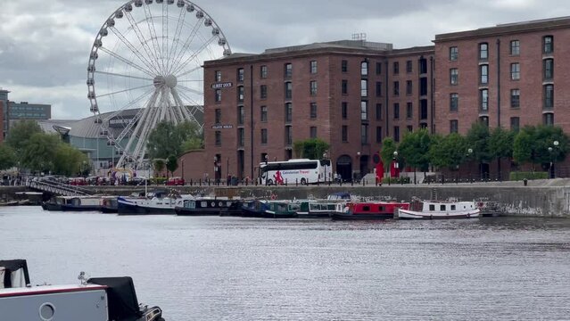 Boats and tour bus by the Royal Albert Dock and Wheel of Liverpool, one of the most-visited tourist attractions in North West England - Liverpool, England, UK
